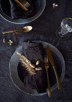 Table decoration in black and gold with fern branches and acorns