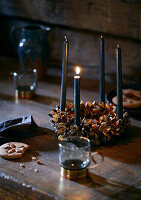 Advent wreath made of golden cones with black candles on a wooden table