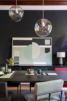 Dining room with black wall, geometric artwork and modern pendant lamps