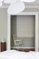 White rocking chair in front of artwork on the wall