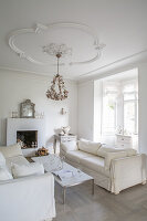 Living room with white sofas, fireplace and chandelier, stucco ceiling