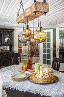 Spring-like dining table with Easter eggs in a nest and wooden beams with hanging lamps