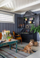 Living room with antique secretary, candlestick and dog on striped carpet