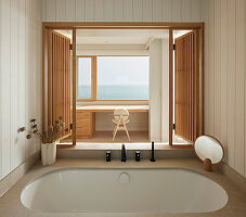 Badezimmer mit Holzverkleidung und Meerblick in modernem Strandhaus