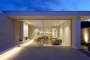 Modern gestalteter Wohnbereich mit Glasfronten bei Dämmerung