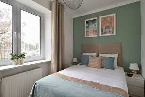 Schlafzimmer mit Doppelbett, grüner Wand und Fensterblick