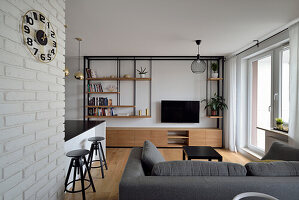 Modern living room with shelving wall, bar counter and brick wall element