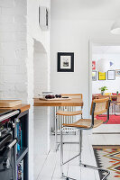 Small breakfast nook with high rattan bar stools and white-painted brick wall