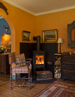 Cozy corner with wood-burning stove and antique furniture in living room in warm yellow tones