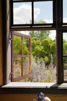 Open wooden windows with a view of the flowering summer garden