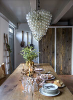 Rustic dining table with candles and Christmas decorations under a large glass lamp