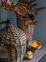 Autumnal decoration with vintage demijohn, dried branches and candlelight