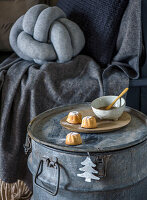 Seating area with grey knotted cushion, blanket and mini cake on zinc vessel