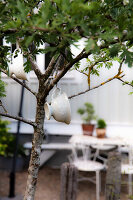 Teacup decoration on garden tree, garden area in the background