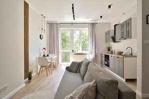 Moderner Wohn-, Koch-, Essbereich mit offener Küche, grauem Sofa und Esstisch