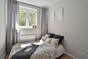 Modernes Schlafzimmer mit grauen Vorhängen und Bildern an der Wand
