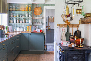 Country kitchen with green cupboards and rustic wood-burning stove