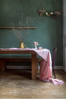 Wooden table with pink linen tablecloth and dried flowers in a jug