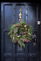 Christmas door wreath made from coniferous branches on a black wooden door