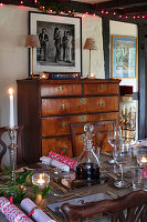 Festively laid dining table in front of antique chest of drawers and ribbon photography