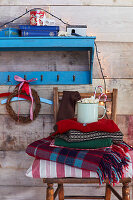 Wooden chair with pile of blankets, hot drink in cup and Christmas decorations
