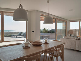 Essbereich mit Holztisch und Blick auf Terrasse und Strand