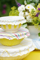 Stacked bowls with fabric covers next to flower arrangement in the garden