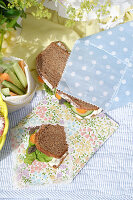Sandwiches in homemade bread bags made of oilcloth on a picnic blanket