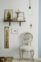 Vintage wooden chair in front of wallpapered wall and shelf with decorative objects