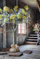 Baum mit Deko aus Trockenblumen, rustikaler Holzboden und Treppe