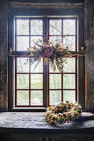 Rustikales Holzfenster mit Trockenblumen und Kranz aus Trockenblumen, Landhausstil