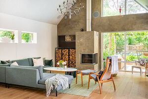 Modern living room with fireplace, chandelier, grey sofa and large windows