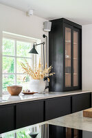 Modern kitchen with black cabinets and glass front, ceramic vase with dried flowers