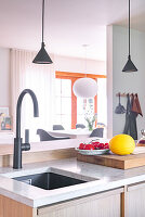Kitchen with black tap, honeydew melon and plate with tomatoes on wooden chopping board