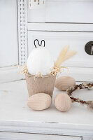 Easter decoration with wooden eggs and bunny figure made of concrete and wire in papier-mâché pot