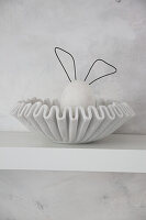 Decorative bunny made of concrete and wire in a bowl on a shelf