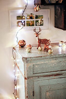 Weihnachtlich dekorierte Kommode mit Lichterkette, Christbaumkugeln und Hirschfiguren