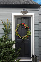 Schwarze Eingangstür mit weihnachtlichem Kranz und Tannenbaum