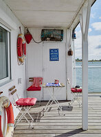 Small veranda of a beach house with folding chairs, table and maritime decoration