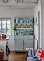 Kitchen cabinet in pastel blue with crockery and decorative elements