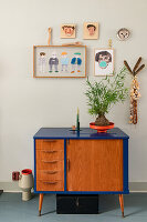 Mid-century sideboard with blue frame, wall decoration and houseplant
