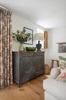 Rustic living room with antique wooden cabinet and patterned curtains