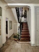 Holztreppe mit schmiedeeisernem Geländer in historischem Flur