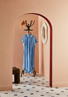 Blue dress on coat rack in hallway with dotted marble floor and round arch