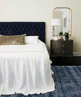 Bedroom with upholstered dark blue headboard and round side table