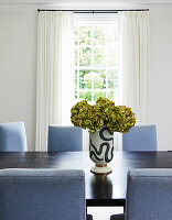 Modern dining area with blue upholstered chairs and decorative vase