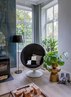 Round armchair and plants next to the fireplace in the modern living area