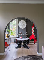 View through arched passageway into dining room with decorative red rocket