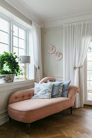 Pink chaise longue with decorative cushions in a classic living room
