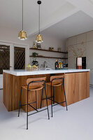 Moderne Küche mit Kochinsel aus Holz, Arbeitsplatte aus Marmor, Barhockern und goldenen Hängeleuchten